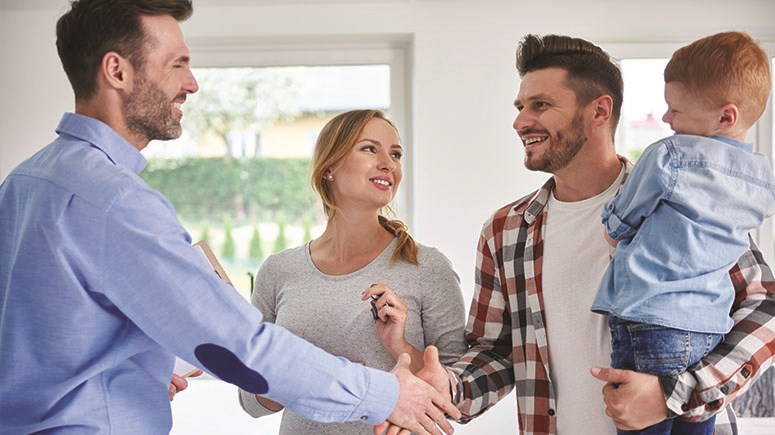 Young family in empty room with another professional , men shaking hands 